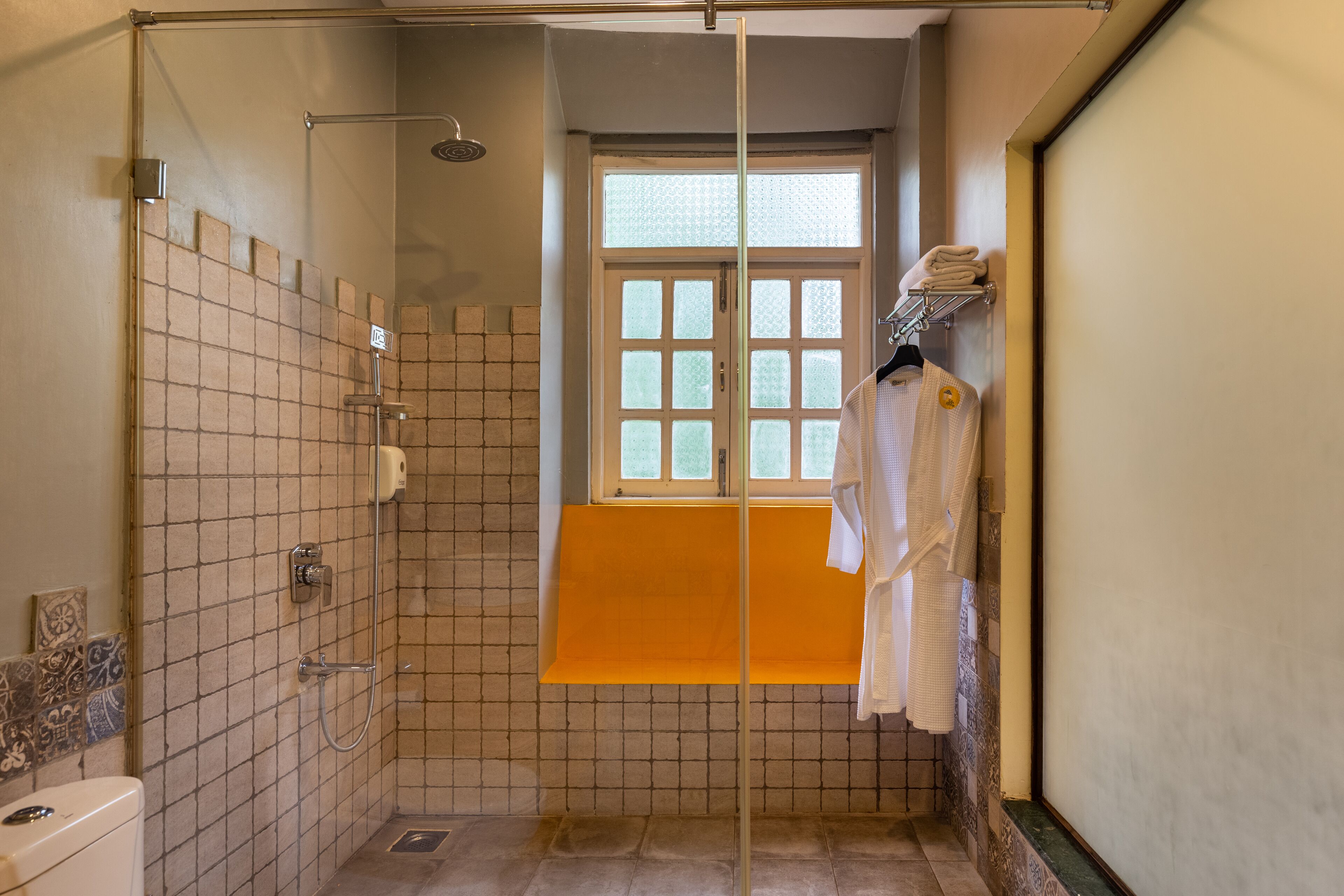 Un baño con ducha, ventana y toallero.