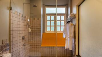 Un baño con ducha, ventana y toallero.