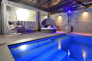 A swimming pool with steps leading into it, surrounded by a hanging chair and a cushioned seating area. - Luxury Villa with heated pool in Zfat (Safed)