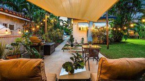 Un espace extérieur aménagé en terrasse, avec des sièges, un barbecue et des guirlandes lumineuses.