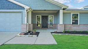 A residential house with a garage, a front door, and a small front yard with plants.