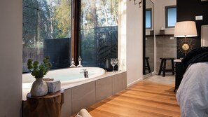 Bathroom features a bathtub, wooden floor, and large mirror.