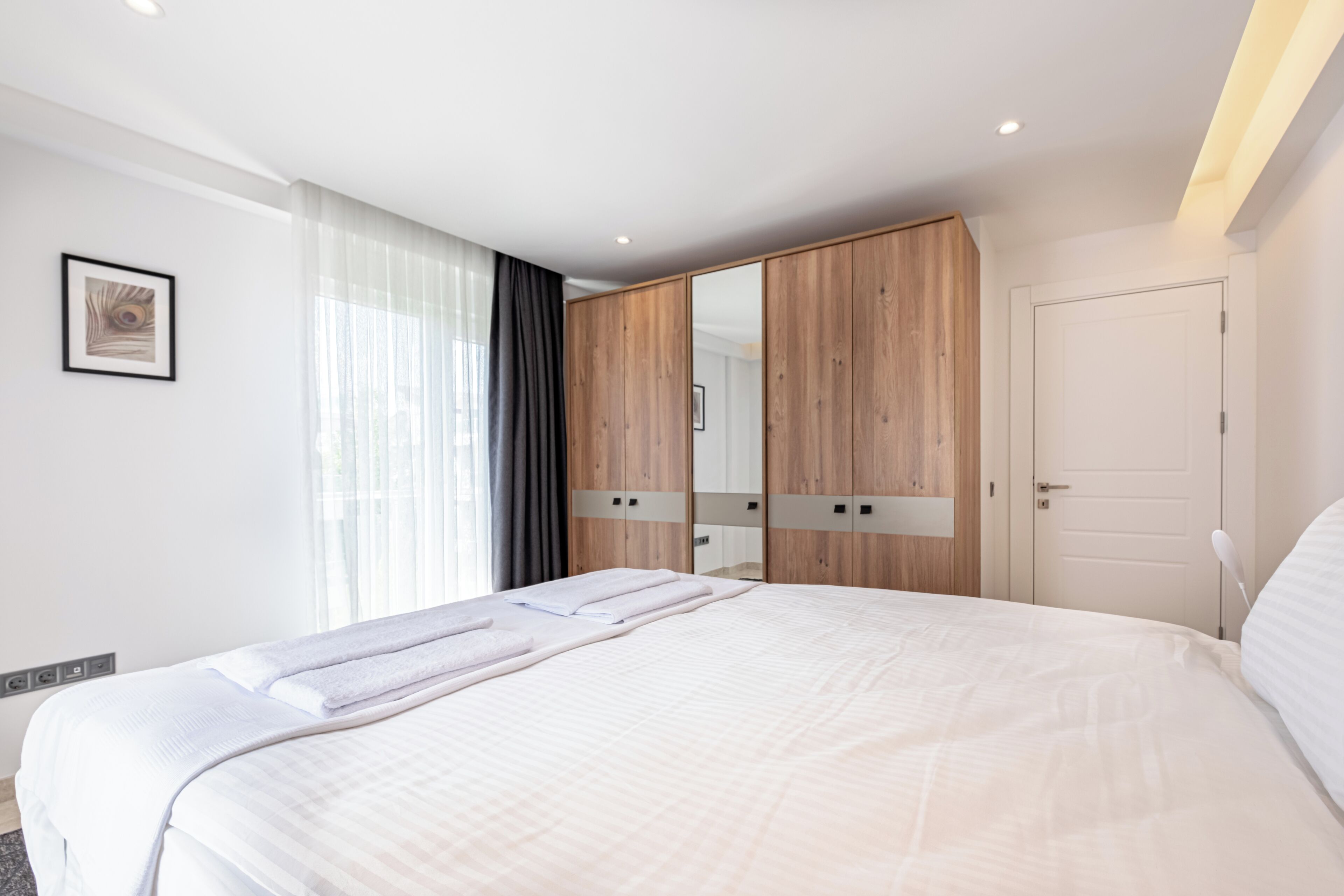 Een moderne hotelkamer met een groot bed, een garderobe met spiegels en een deur.