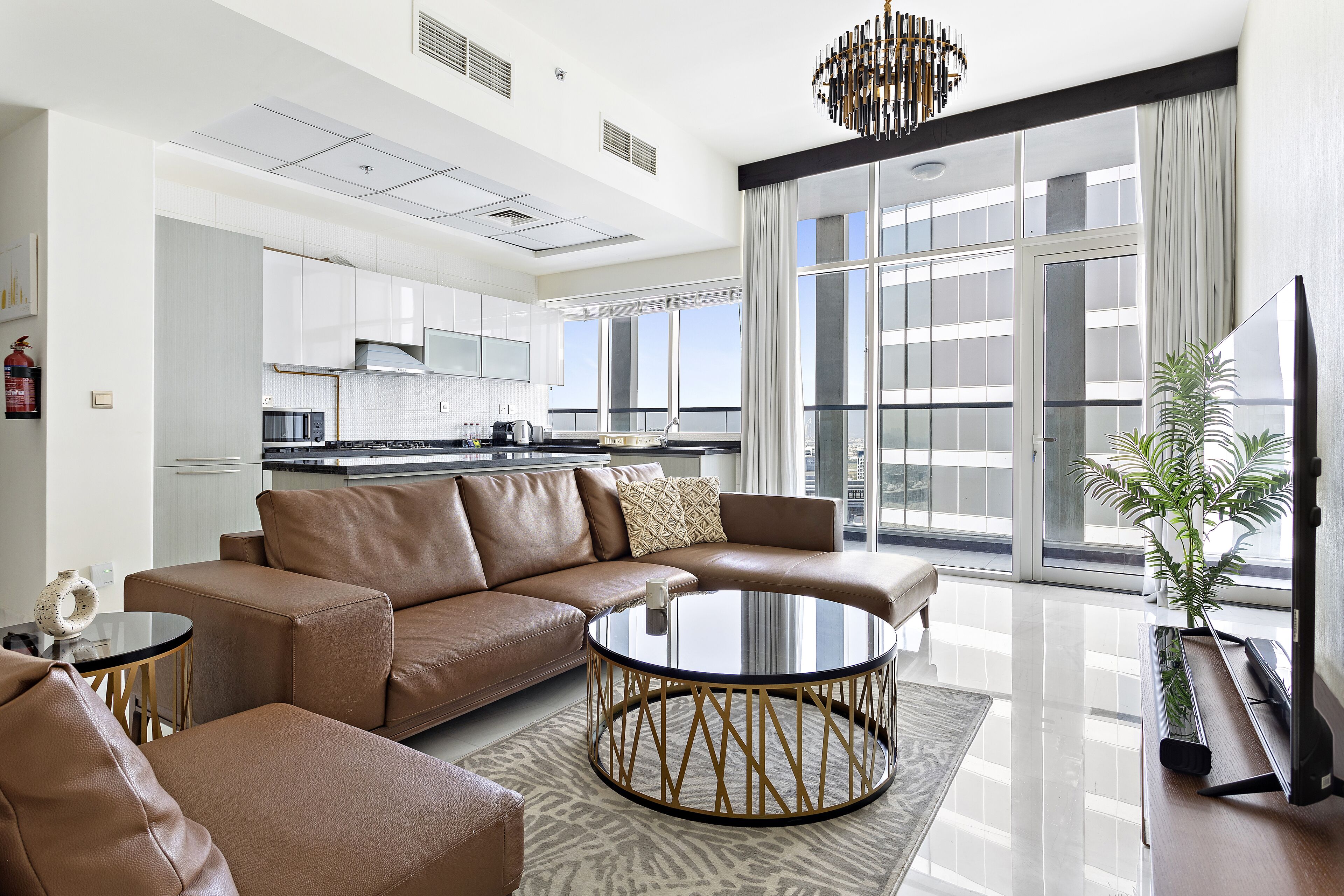 A modern living room with a brown leather sofa, a glass coffee table, and a flat-screen TV.