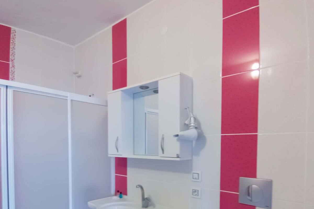 Ein Badezimmer mit Waschbecken, Spiegel und Toilette, sowie einer Wand mit roten Fliesen.