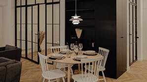 Un coin repas avec une table ronde, des chaises blanches et un buffet noir.