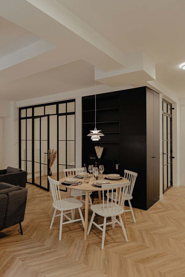 A dining area with a round table, white chairs, and a black cabinet.