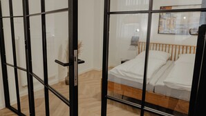 Une chambre avec un lit, une table de chevet et une fenêtre donnant sur un immeuble.