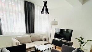 Un salon moderne comprenant un canapé, deux fauteuils, une table basse, un téléviseur et un lampadaire.