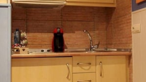 Une cuisine avec des meubles en bois, un évier en acier inoxydable et un mur de fond en briques.