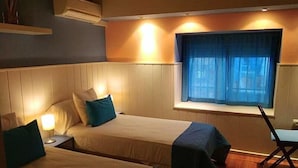 Une chambre avec deux lits, une fenêtre avec des rideaux bleus et un bureau avec une chaise.