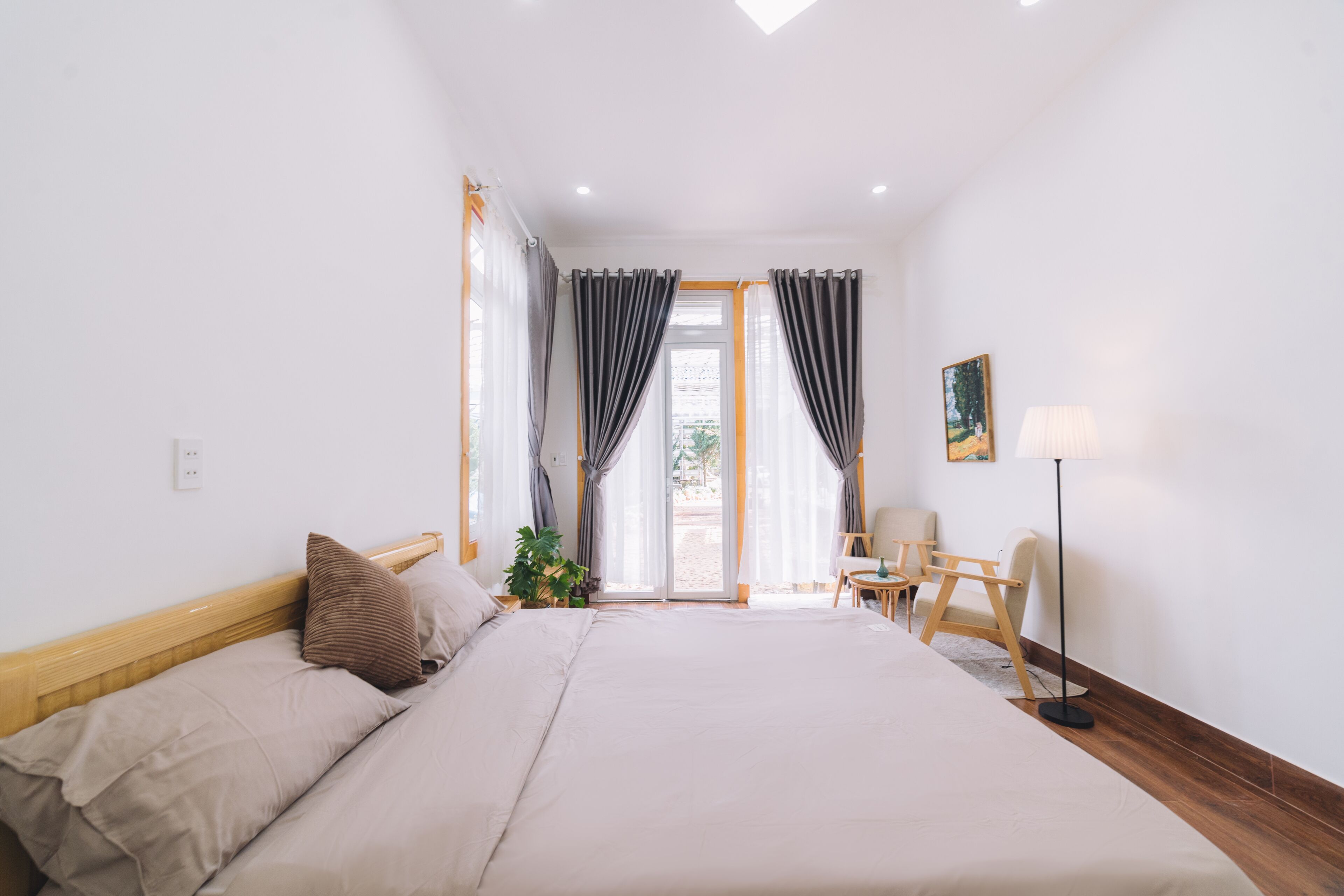 Un dormitorio con una cama grande, una silla, una mesita y una lámpara.