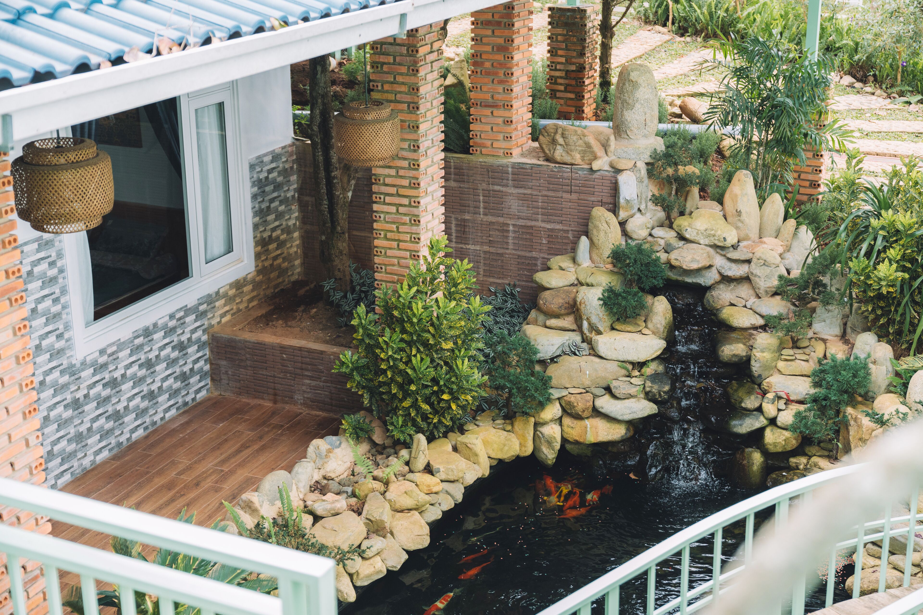 A garden with a pond, stone walls, and a wooden deck.