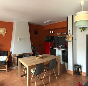 Un espace de vie compact comprenant un coin repas, une cuisine et un petit coin salon.