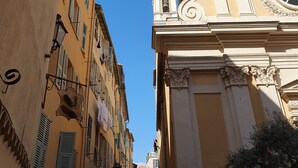 A narrow street with buildings featuring balconies and a church with ornate architecture. - OLD City in Style: Bright, Spacious & Comfortable (Nice)
