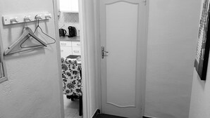 A narrow hallway with a white door, a coat rack with a hanger, and a tiled floor. - OLD City in Style: Bright, Spacious & Comfortable (Nice)