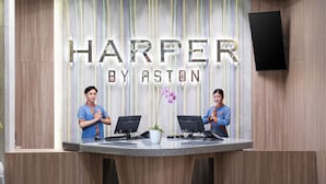 Un mostrador de recepción con un letrero que dice "HARPER BY ASTON" y dos empleados detrás.
