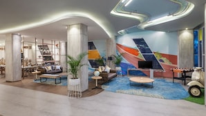 Un vestíbulo moderno con techo curvo, un mural colorido y una zona de estar con sofás y una mesa de centro.