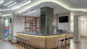 Zona de bar moderna con mostrador curvo, taburetes y un pilar grande.
