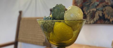 A glass bowl with a lemon and an artichoke on a wooden table.