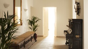 A hallway with a bench, a large mirror, potted plants, and a cabinet. - Casa Pizarro Hotel (Cáceres)