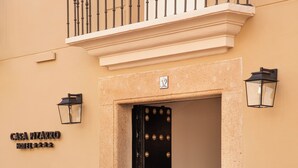 A hotel entrance with a black door, a bench outside, and a sign reading "CASA PIZARRO HOTEL". - Casa Pizarro Hotel (Cáceres)