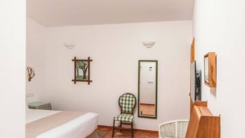 A bedroom with a bed, a chair, a crib, a wooden cabinet, and a skylight.