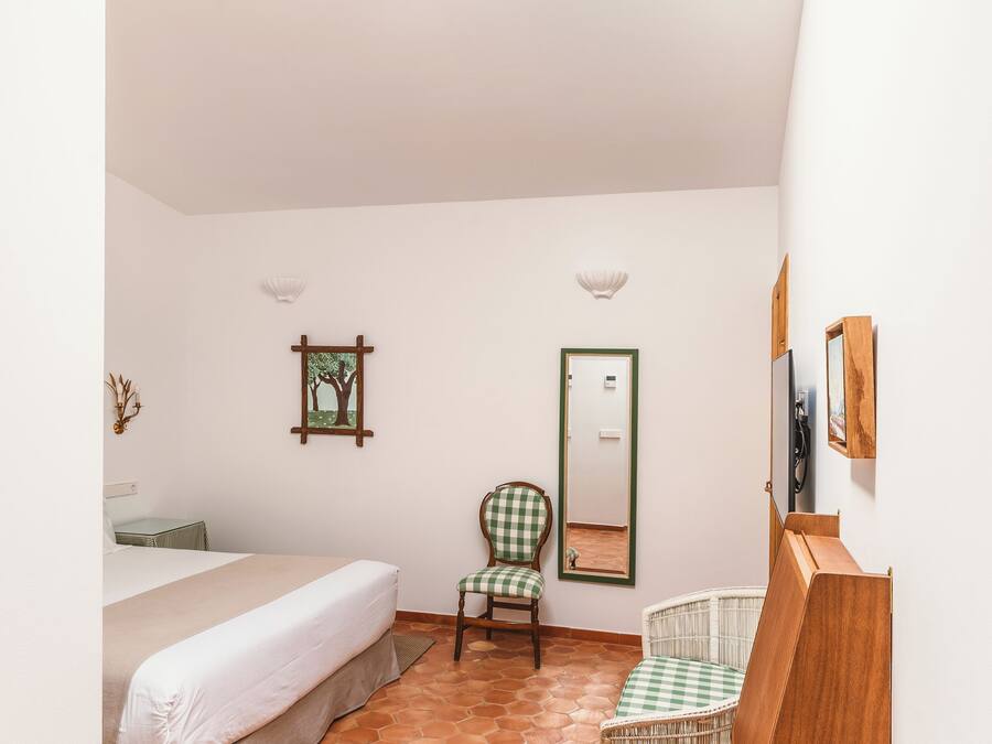 Un dormitorio con cama, una silla, una cuna, un armario de madera y un tragaluz.