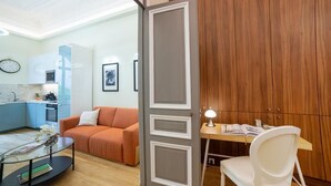 Una sala moderna con un sofá, una mesa de centro de vidrio y una mesa de comedor de madera con una silla.