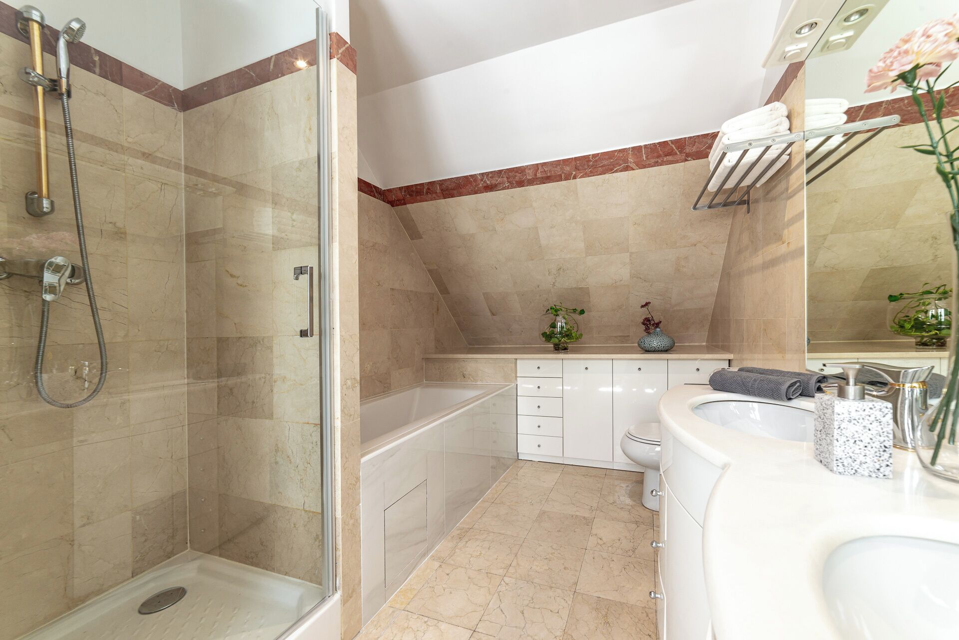 Een moderne badkamer met een douche met glazen wand, een bad, een wastafelmeubel en een toilet.