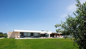 Una casa moderna con fachada de piedra, amplios ventanales y mobiliario de exterior.