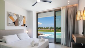 Un dormitorio moderno con una cama grande, un ventilador de techo y vista a una piscina a través de un ventanal corredero.