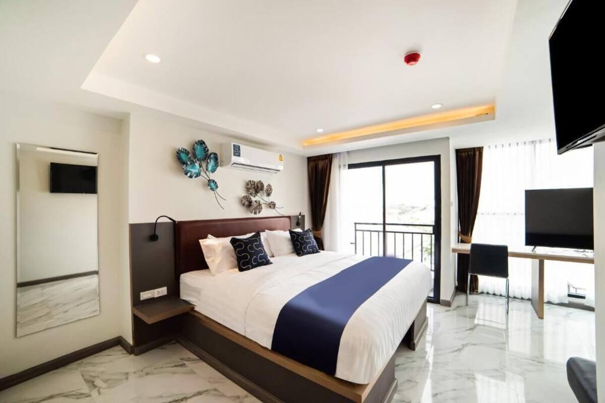 Une chambre d’hôtel moderne dotée d’un grand lit, d’une télévision, d’un balcon et offrant une vue sur l’extérieur.