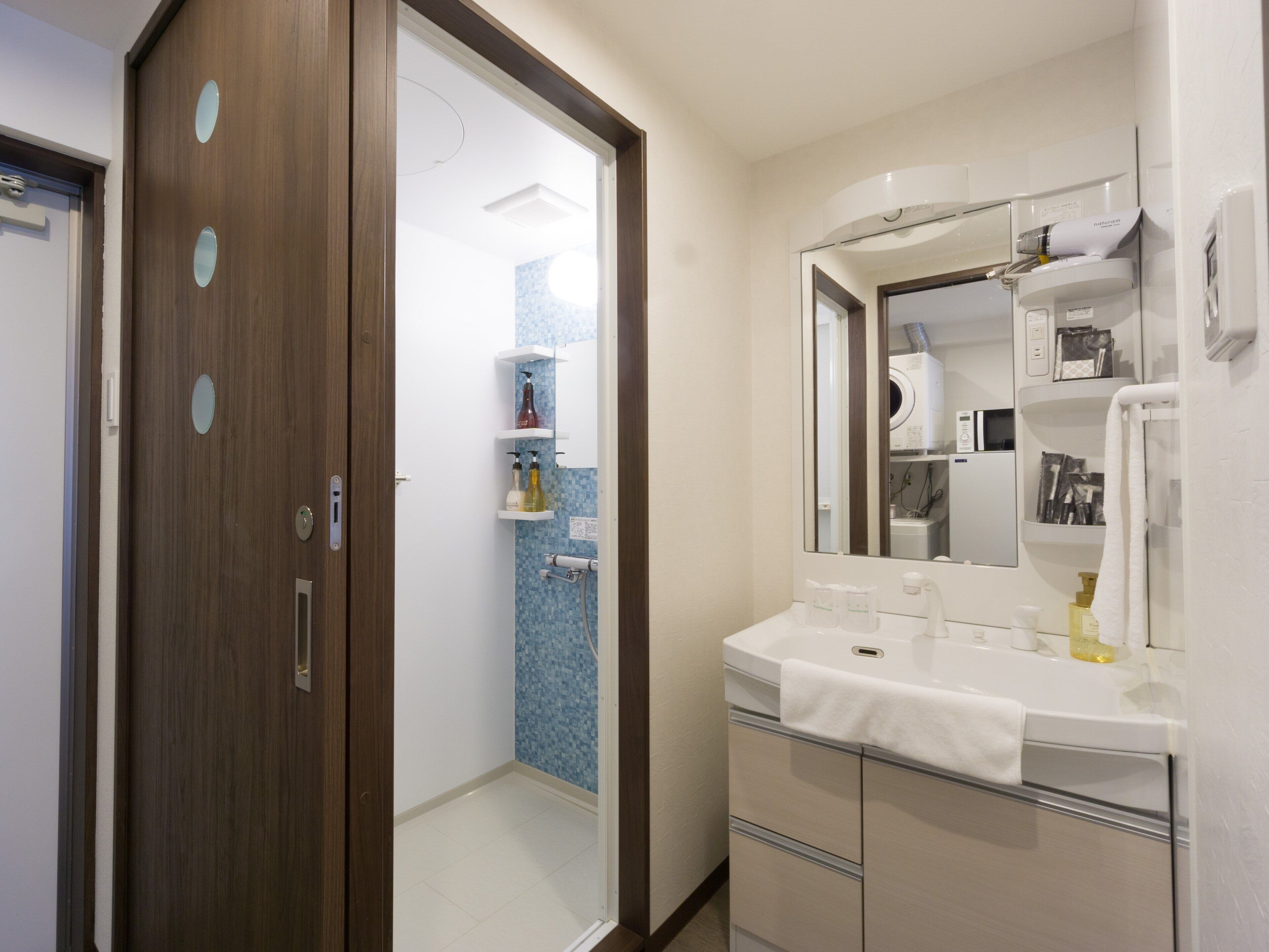 Un baño con puerta de madera, un lavamanos blanco y un espejo.