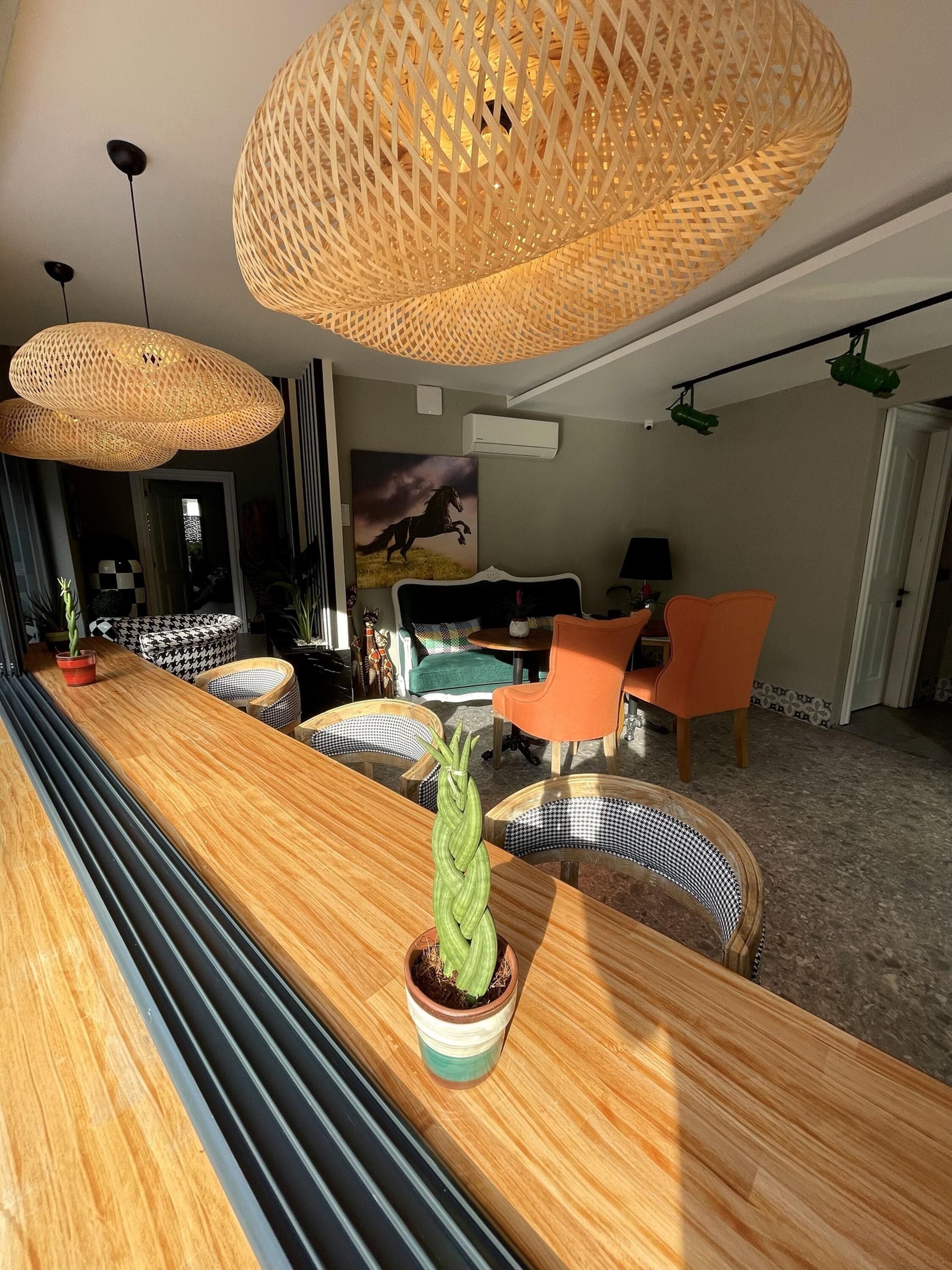 A modern living room with a wooden coffee table, wicker pendant lights, and a potted plant.