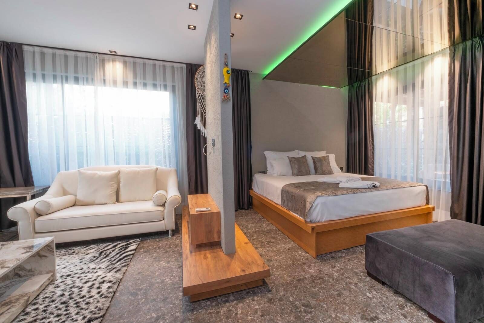 Una habitación de hotel moderna con cama, sofá, una mesita y un pilar decorativo.