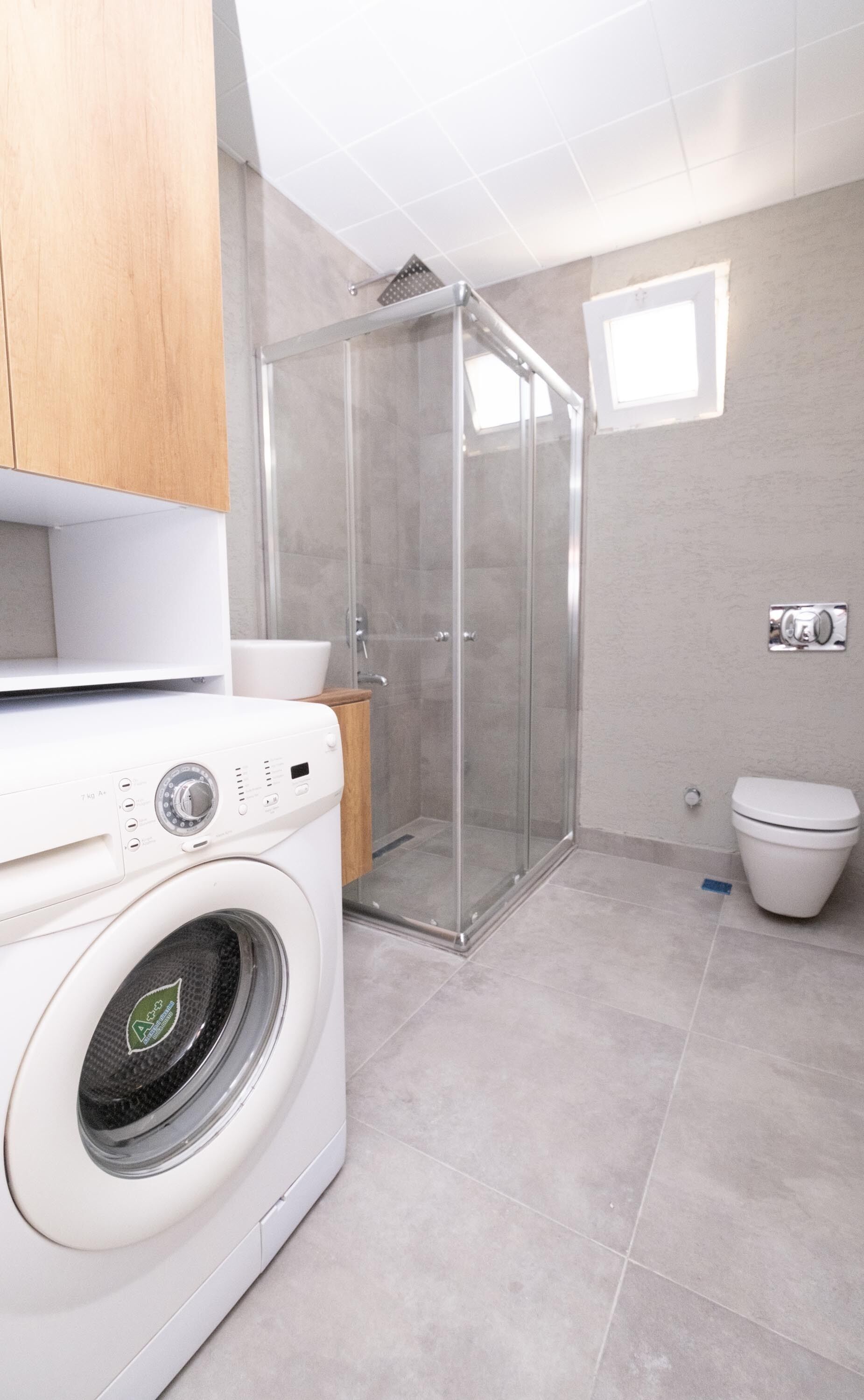 Ein modernes Badezimmer mit Duschkabine, Waschmaschine und Toilette.
