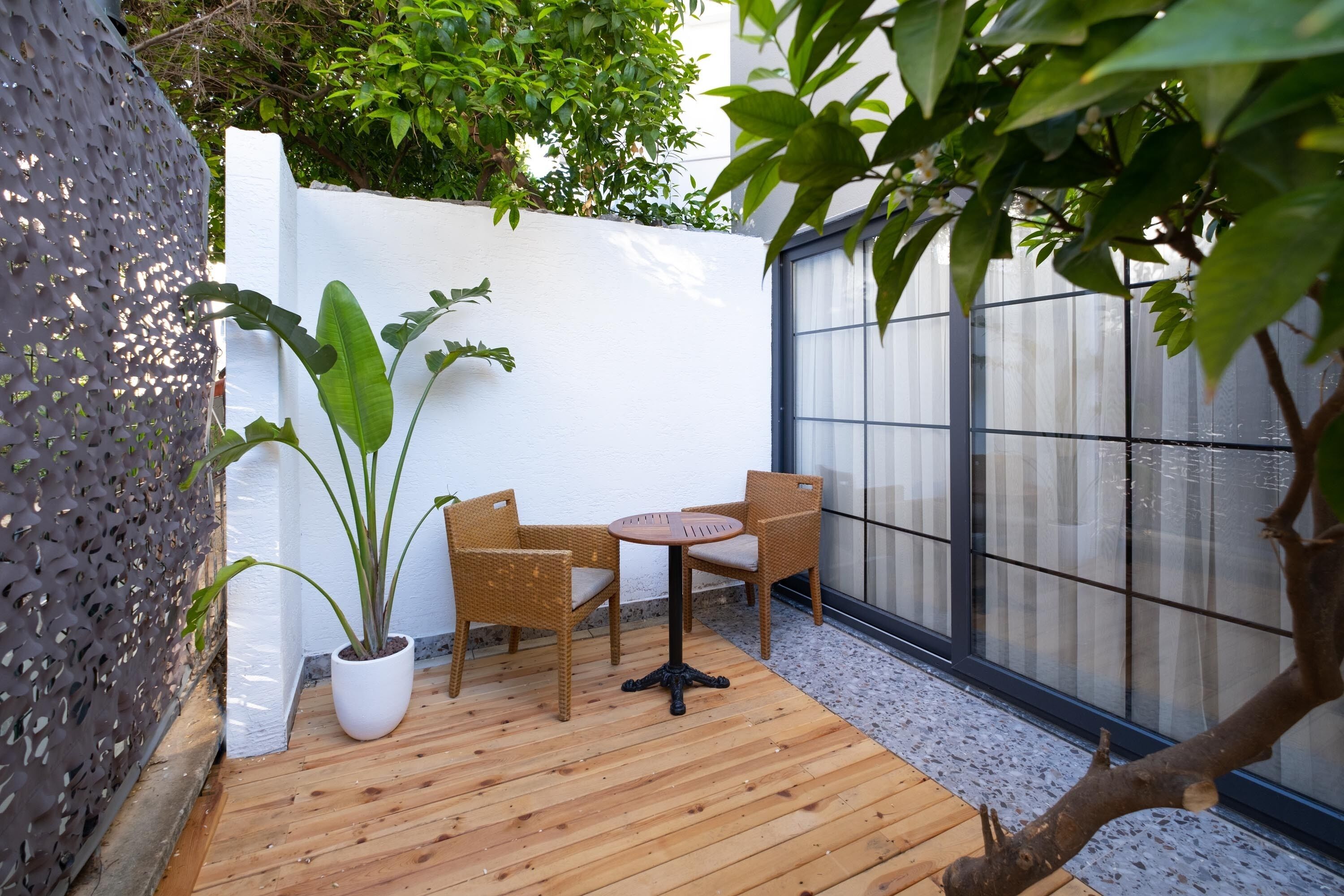 A wooden deck with a table and chairs, surrounded by a white wall and a glass door.