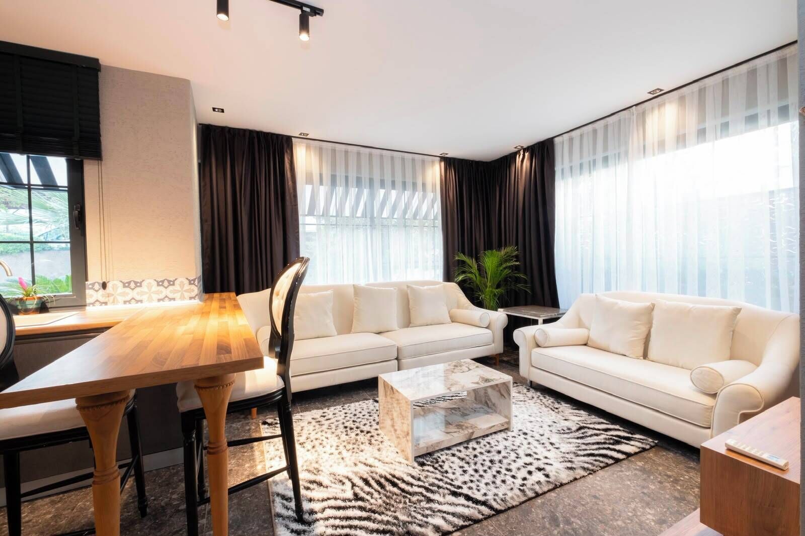 Una sala de estar moderna con un conjunto de sofás, una mesa de centro y una mesa de comedor.