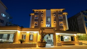 A modern hotel with a prominent 'W' sign, large windows, and a well-lit entrance area with potted plants. - Wolf Suites (Antalya)