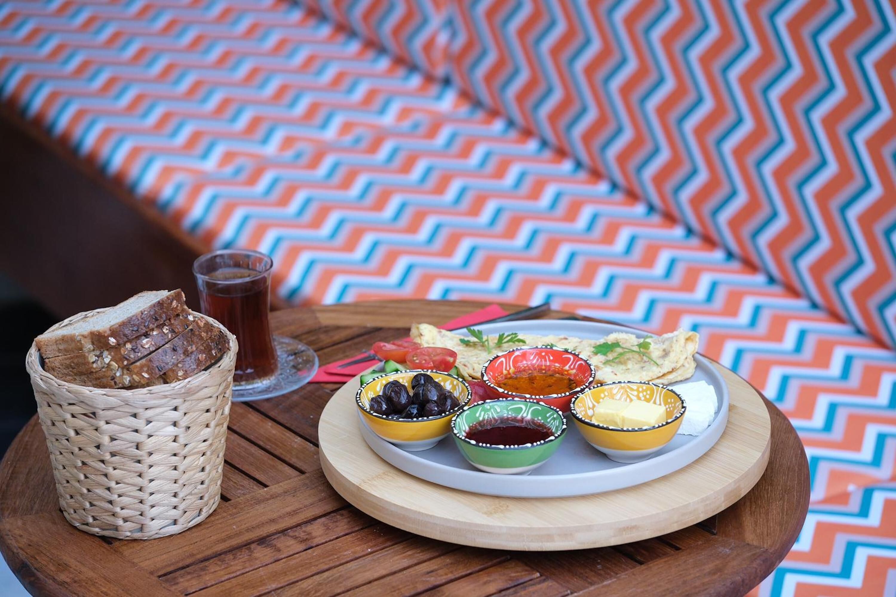 Una comida con pan, aceitunas, tomates y una bebida sobre una mesa de madera.