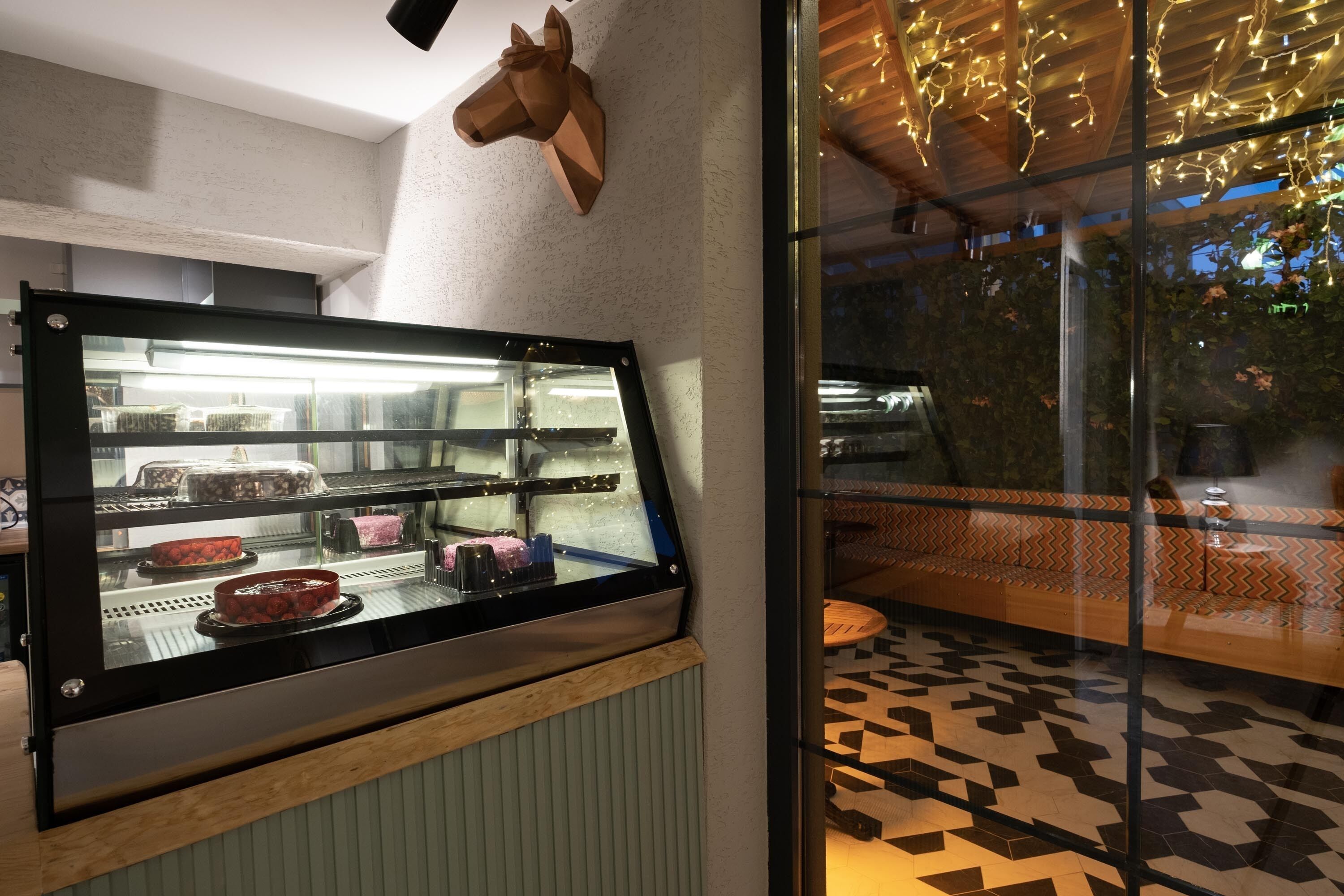 Een vitrine met gebak en een houten hoofdschulptuur aan de muur.