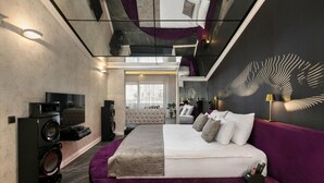A modern bedroom with a large bed, a television, and a sound system. - Wolf Suites (Antalya)