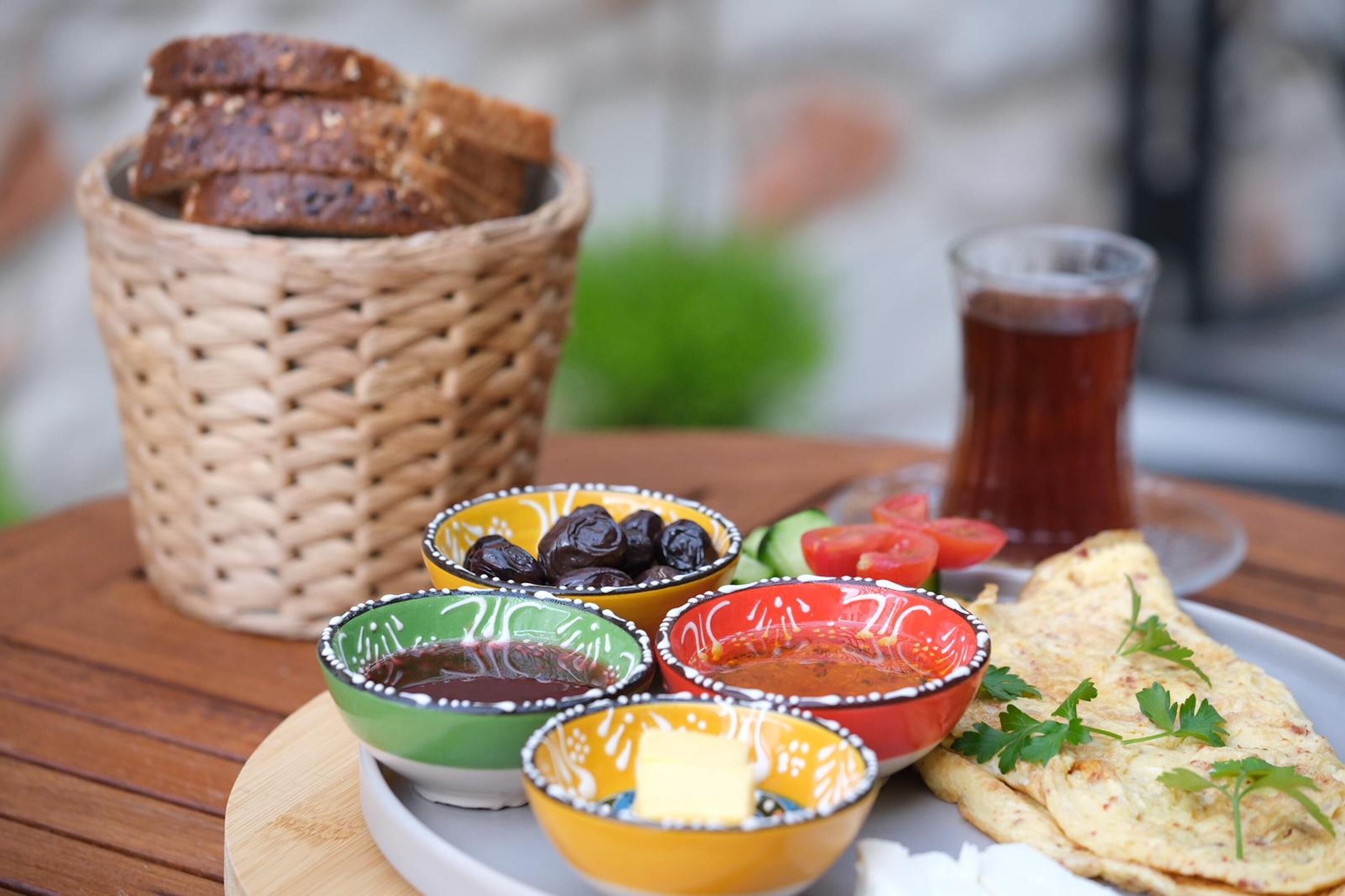Ein Tisch mit einem Teller Fladenbrot, einem Korb Brot und bunten Schalen mit Dips und Gemüse.