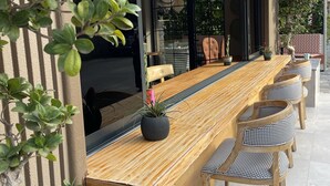 An outdoor dining area with a long wooden table, cushioned chairs, and hanging rattan lamps. - Wolf Suites (Antalya)