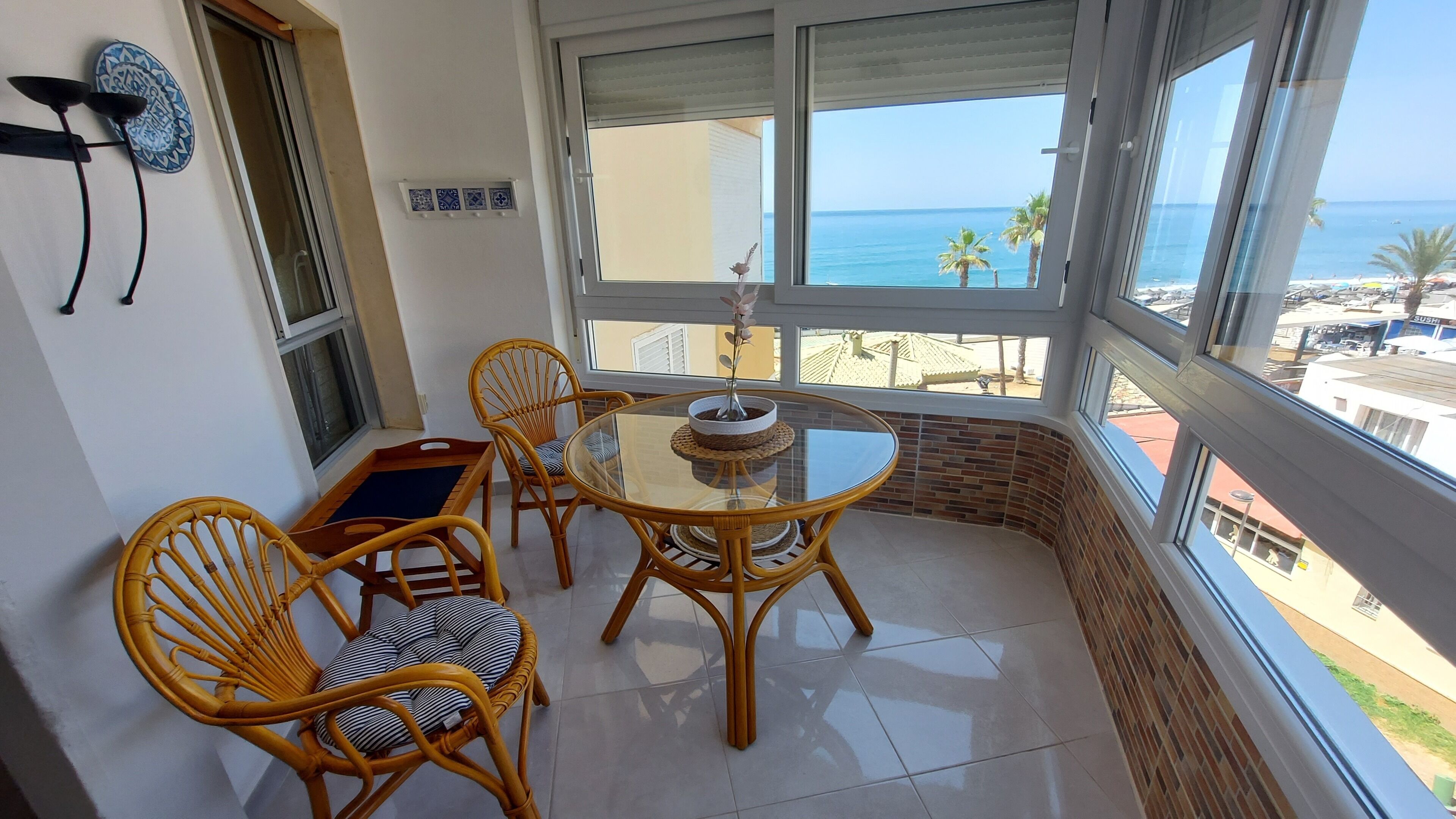Ein Balkon mit Korbstühlen, einem Glastisch und einem Blumentopf.