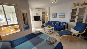 Una sala de estar con un sofá, sillones, una mesa de centro y un televisor.
