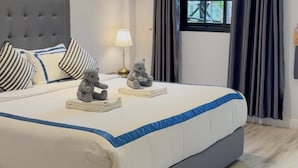 A neatly made bed with a grey headboard, striped pillows, and a blue accent on the bedspread. - Macchiato Resort Savannakhet (Savannakhet)