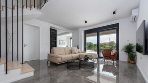 A modern living room with a beige sofa, a brown armchair, and two coffee tables.