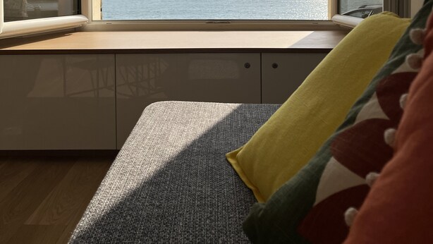 A room with a large window overlooking a body of water, a wooden floor, and a bed with a patterned pillow. - Appartment 2 rooms - Ocean View (Saint-Jean-de-Luz)